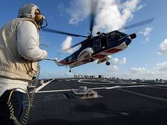US Navy 091006-N-1688B-184 Interior Communications Electrician 1st Class Ryan Ratts, the flight deck safety officer aboard the guided missile destroyer USS Cole (DDG 67), observes a British civilian helicopter land during fligh